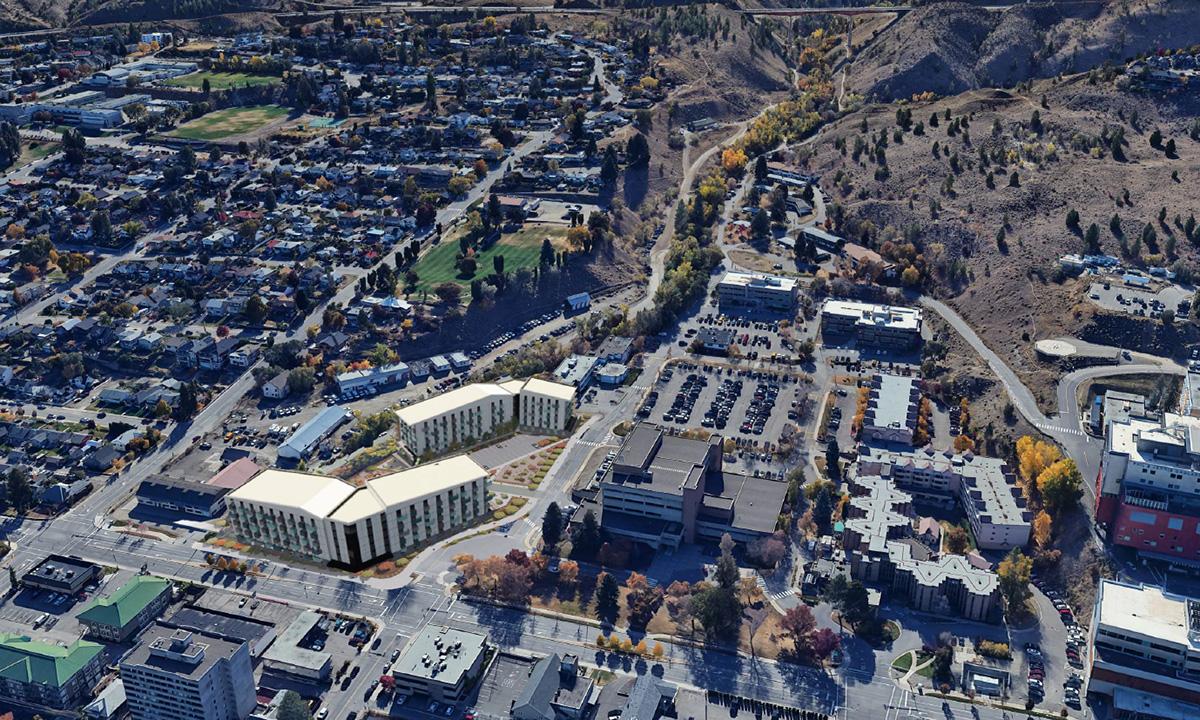 Aerial view of a cityscape with residential buildings, parking lots, and surrounding hills.